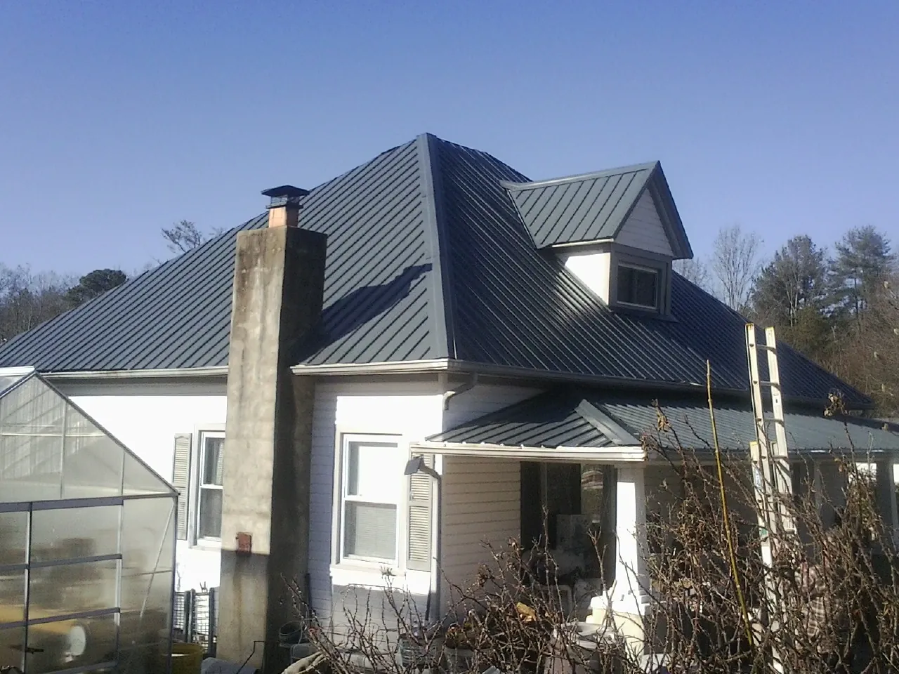 Dark blue standing seam metal roof on a white farmhouse with dormer — Slate & Tile Roof Repair by Roofing Brothers in Brinklow