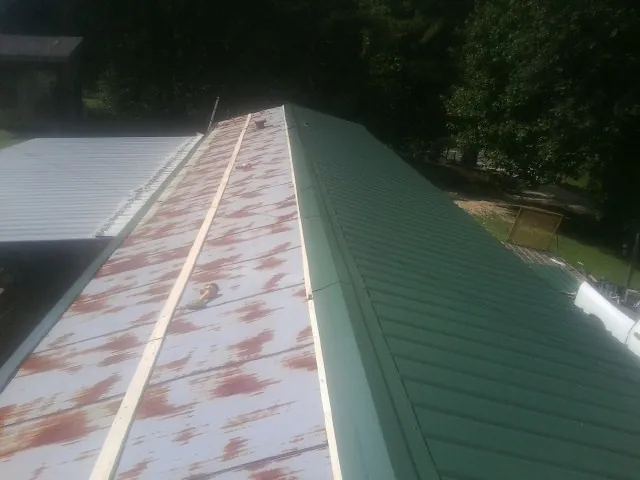 Old rusted panels beside newly installed green metal roofing — Wind Damage Roof Repair by Roofing Brothers in Brinklow