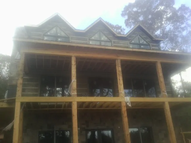Dormers and porch framing on a large log home under construction — Roof Coating work by our crew in Brinklow