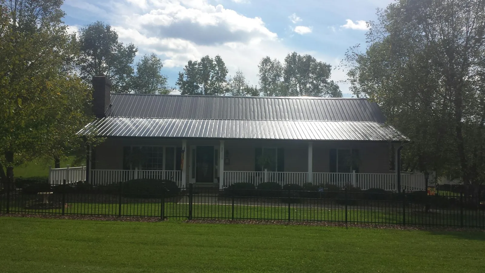 Gray metal roof on a brick ranch with a full width front porch — Gutter Guard Installation work by our crew in Brinklow