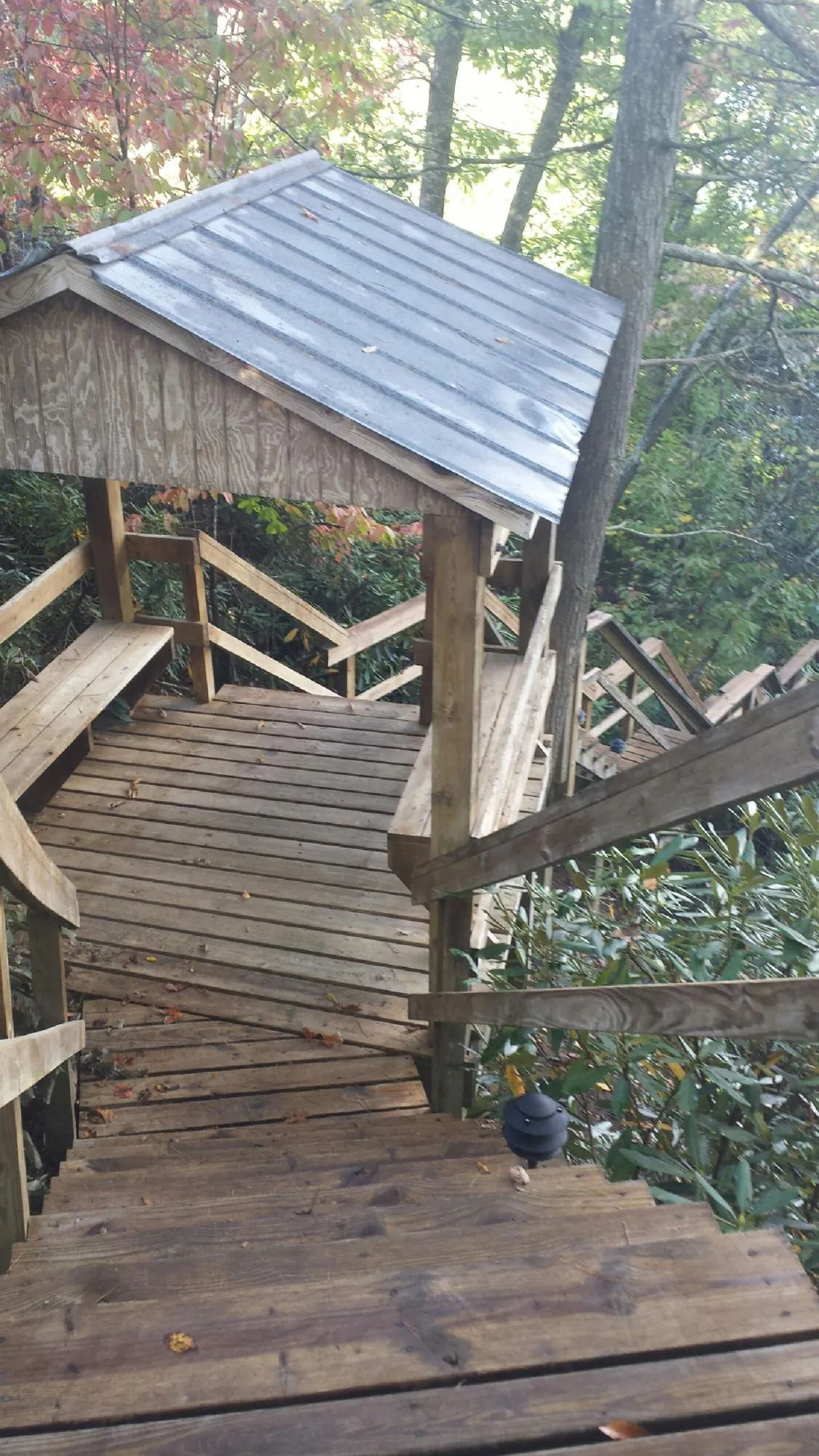 Metal roofed shelter over wooden steps on a wooded walkway — Skylight Repair & Installation work by our crew in Brinklow